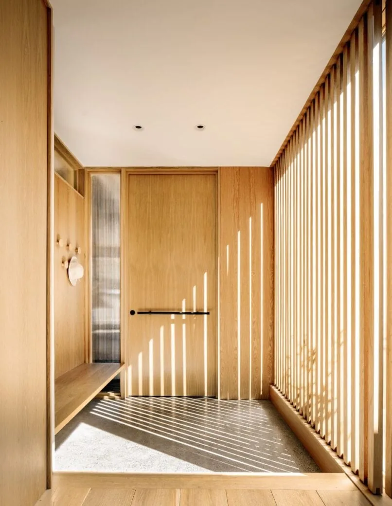 Entry space of Cupertino Courtyard House featuring vertical wood slats and built-in bench by SHED Architecture & Design.