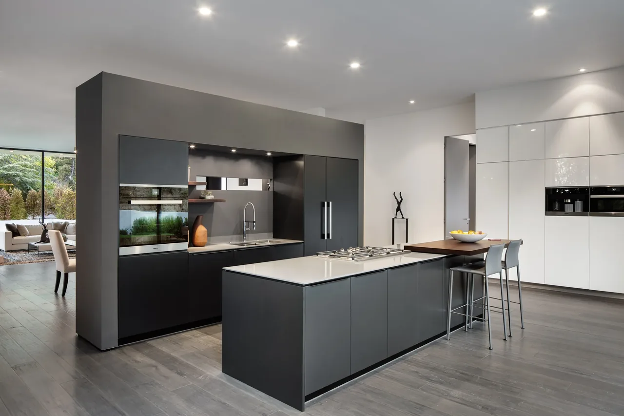 Open kitchen layout featuring dark gray cabinetry with integrated appliances and a large island with a gas cooktop.