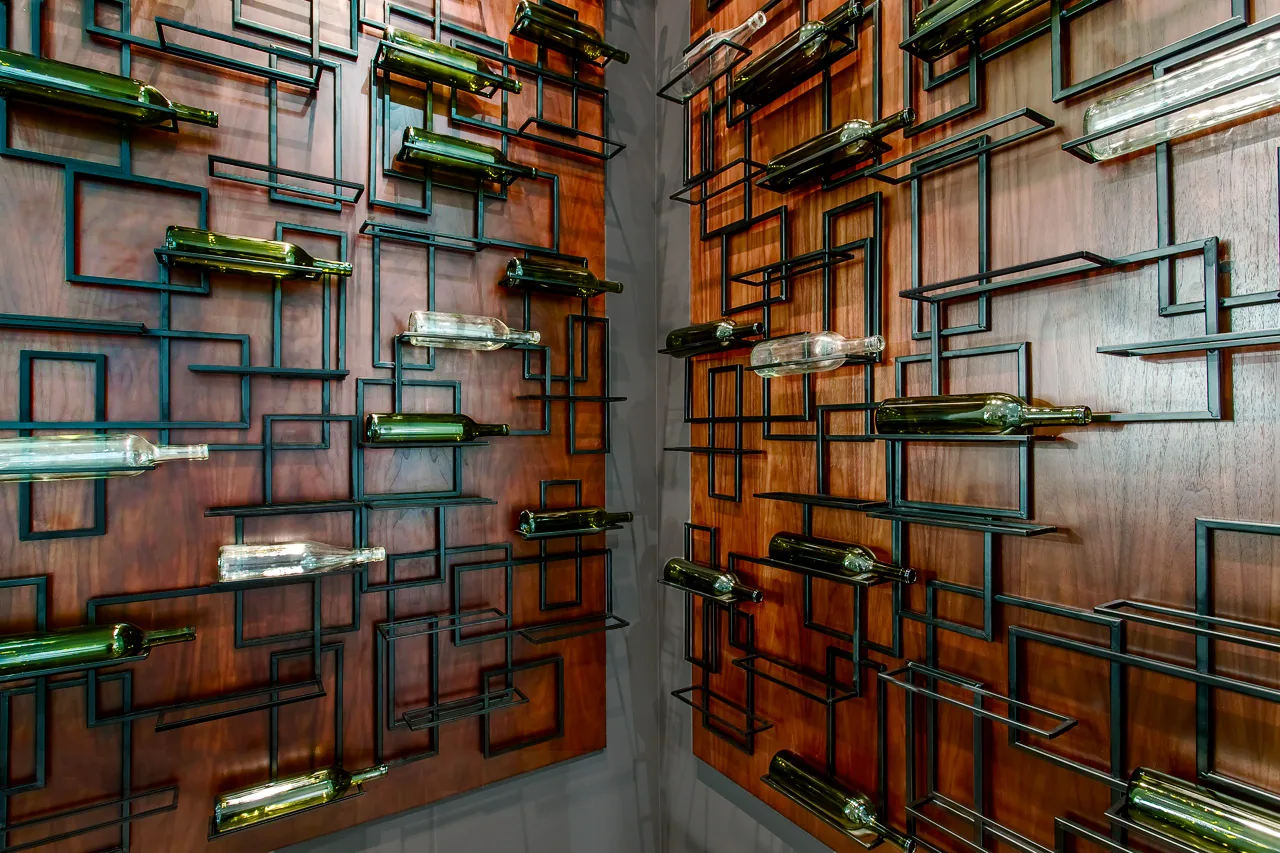 Metal and wood geometric wine rack with empty bottles serves as wall-mounted decor.