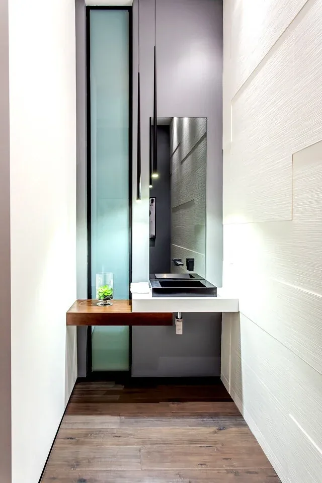 Narrow bathroom with a floating wood shelf, black rectangular vessel sink, and textured wall panels.