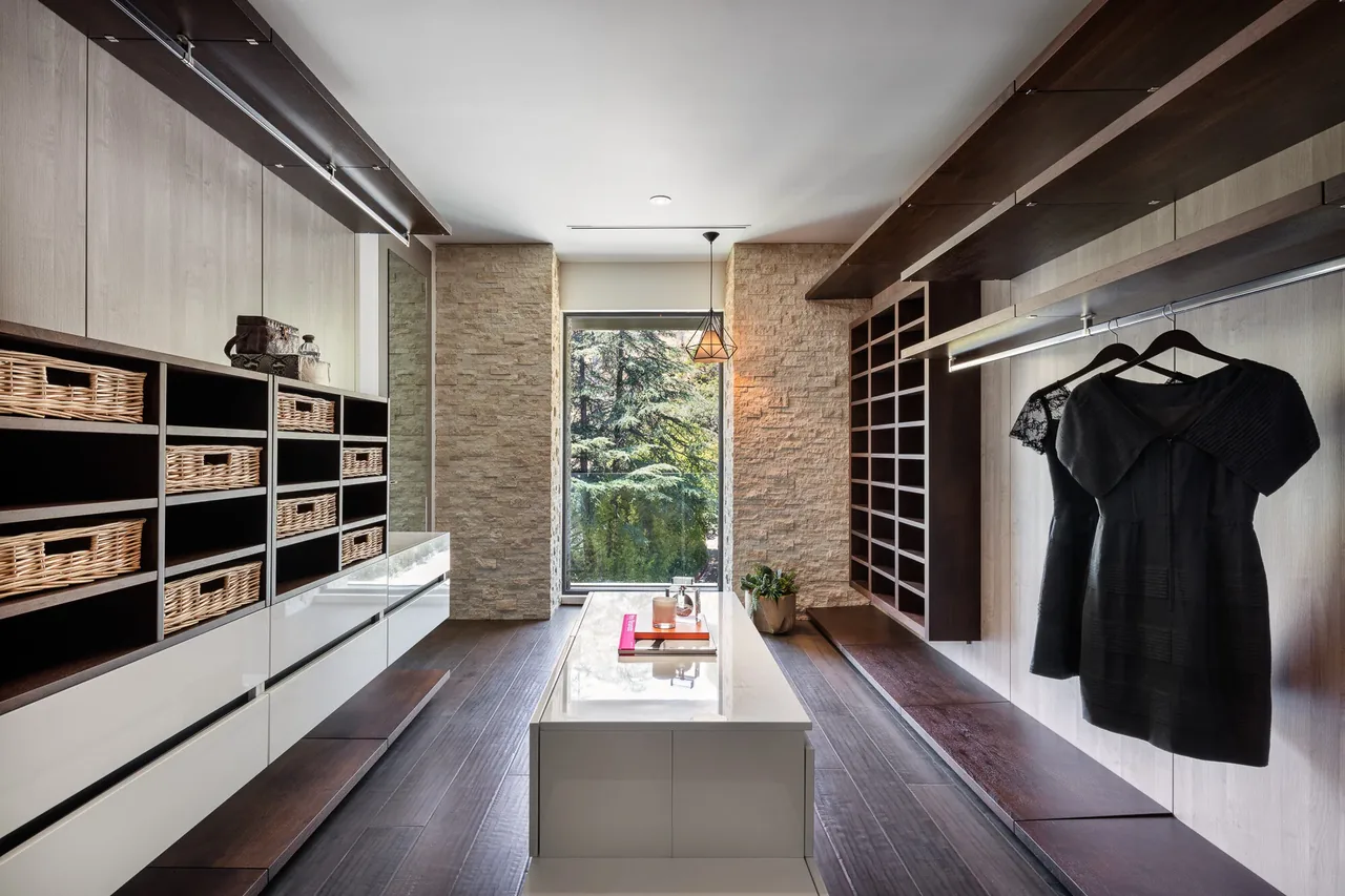 Closet with custom built-in shelves, hanging space, and a large window at the end providing natural light.