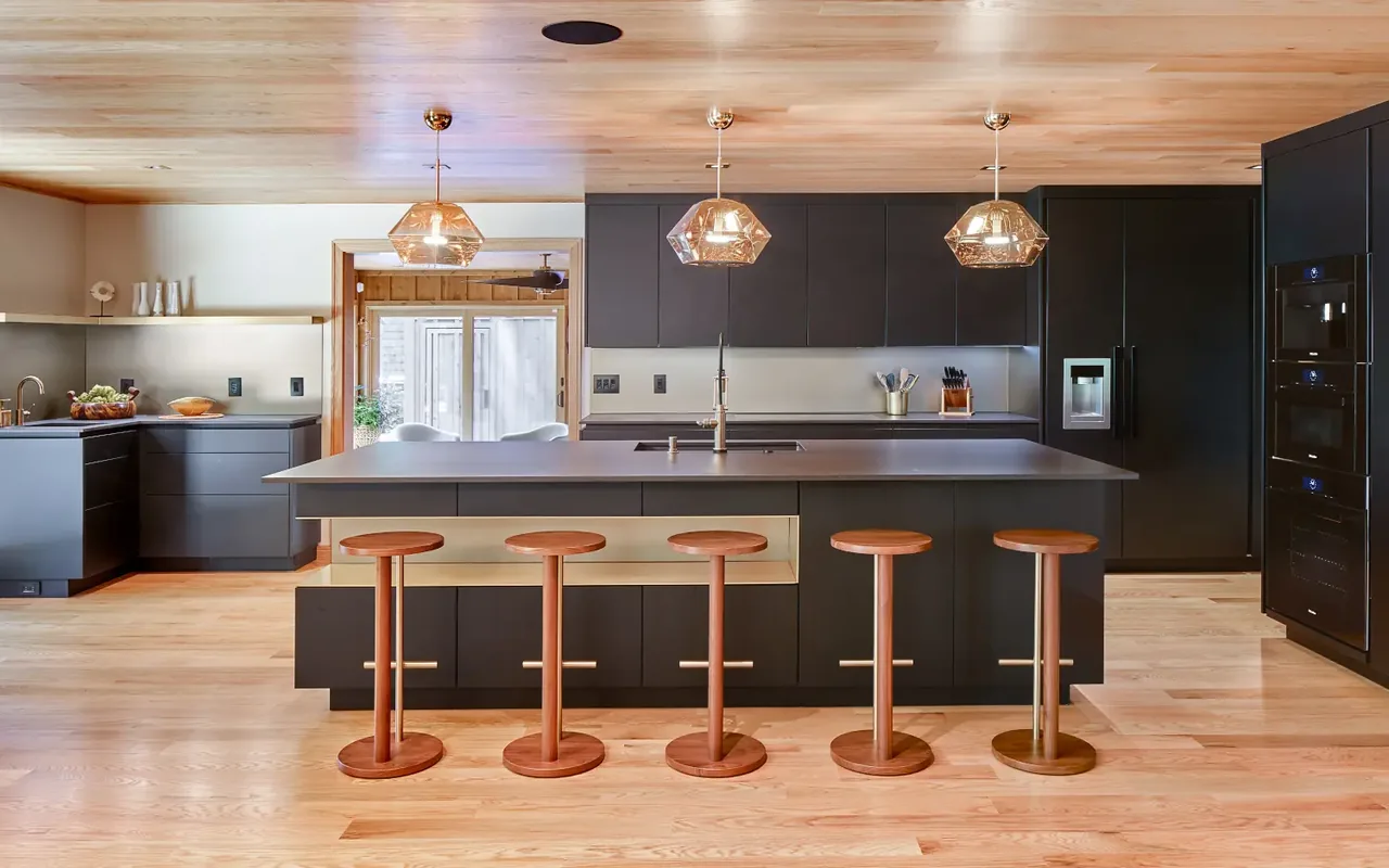 The Tidewater project features a kitchen with dark cabinets, a large island with wood stools, and pendant lighting.