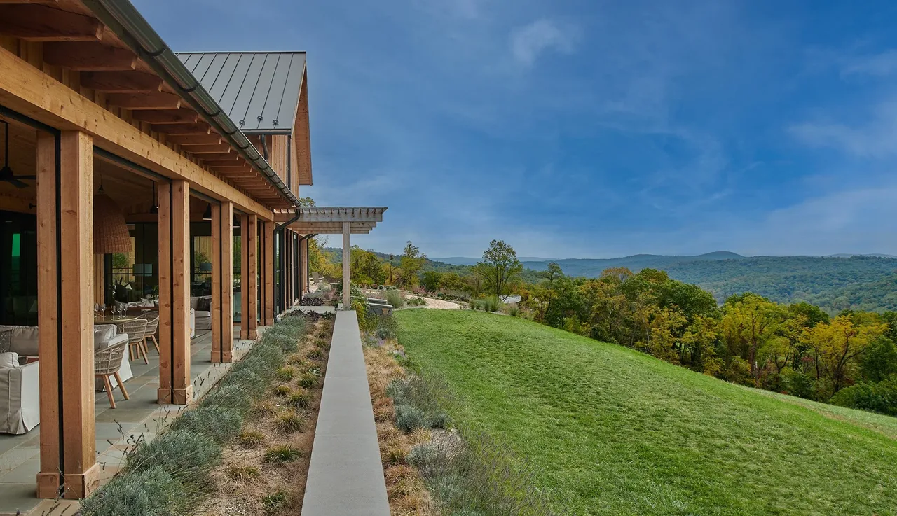 Exterior side view of a timber-framed porch with outdoor seating at Crimson Lane Vineyard, showing natural landscaping and hillside view.
