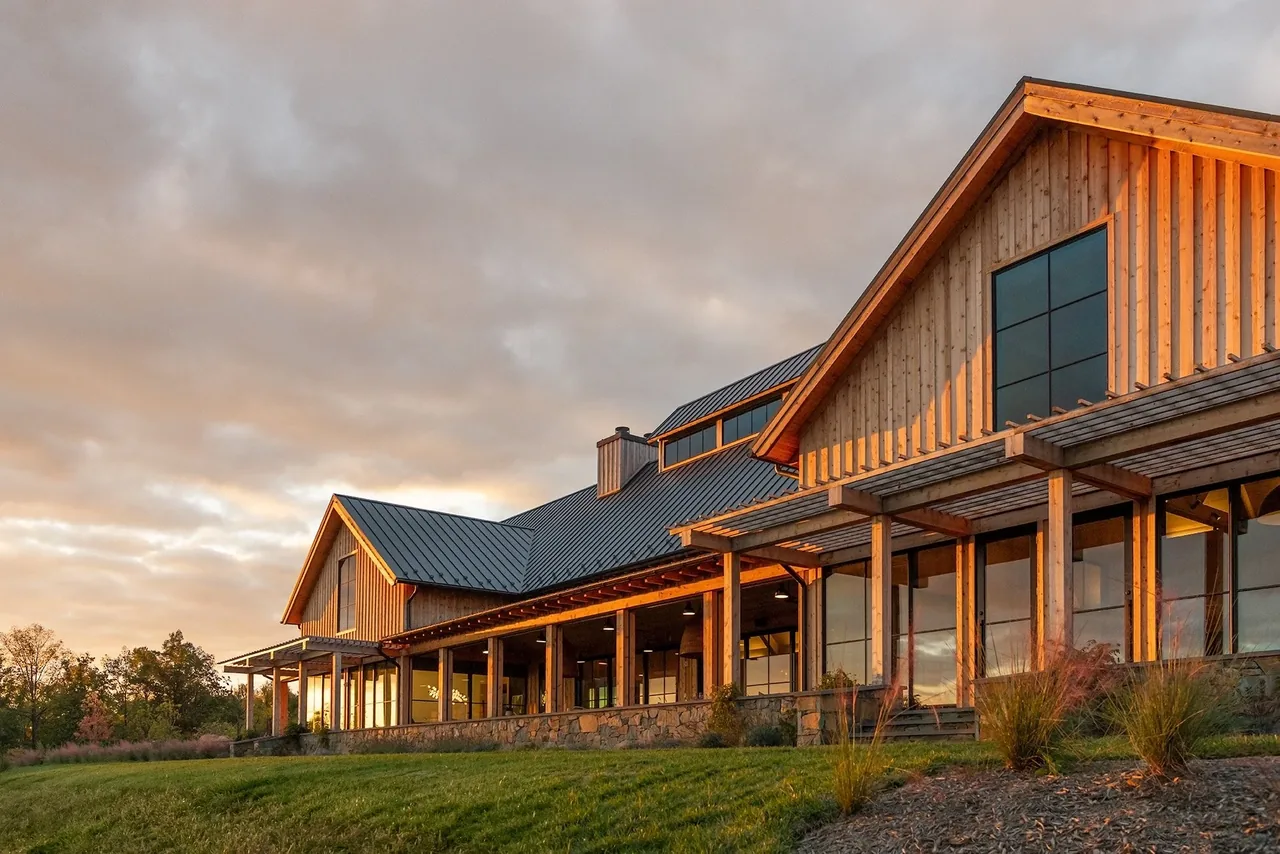 Crimson Lane Vineyard features timber framing with triangular gable roofs and metal roofing at sunset.