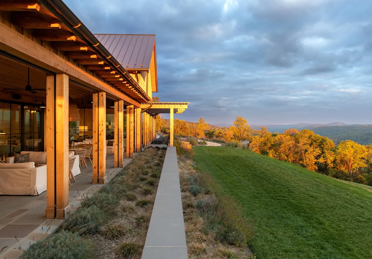 Wood-framed outdoor seating space with pergola and natural landscape at Crimson Lane Vineyard by Moore Architects.
