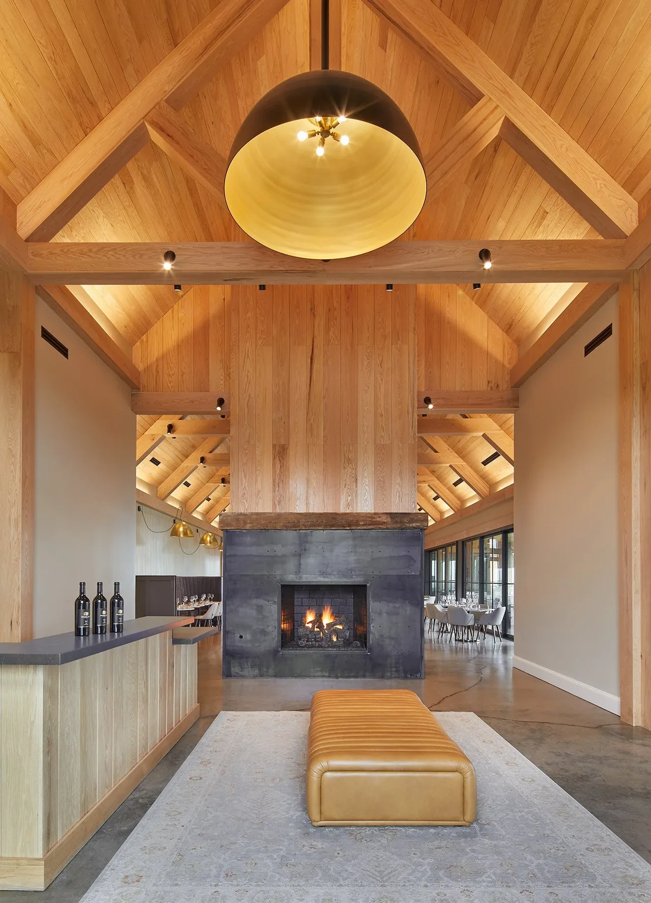 Crimson Lane Vineyard interior features a vaulted ceiling, double-sided fireplace, and leather bench seating in a timber-framed space.