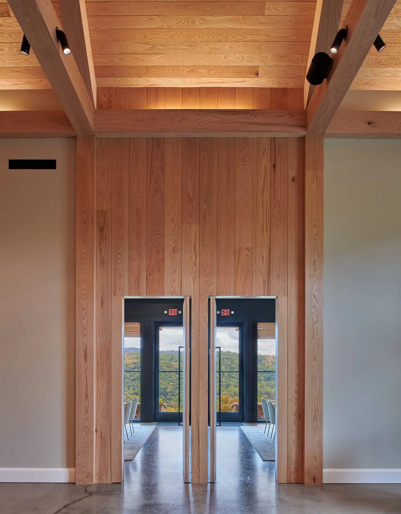 Interior wood-paneled hallway at Crimson Lane Vineyard with doors reflecting a mountain view.