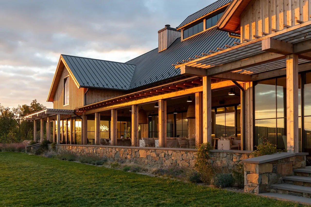 Crimson Lane Vineyard features timber framing, stone landscaping, and a metal standing seam roof with a pergola-covered porch.