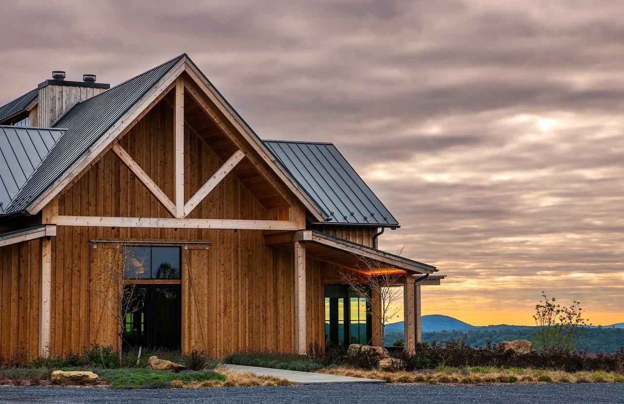 Exterior view of a wood-sided building with triangular gable and metal roof at sunset.