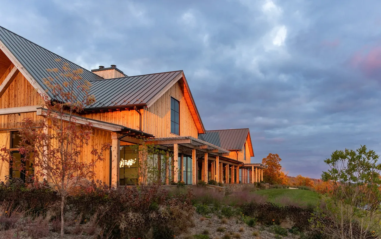Crimson Lane Vineyard features timber framing and triangular gables with natural stone and gravel landscaping at sunset.