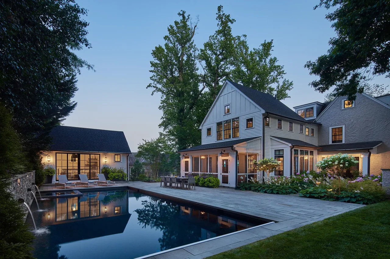 Backyard features include a rectangular pool with water spouts, patio seating, and a two-story house combining white siding and stucco finishes.