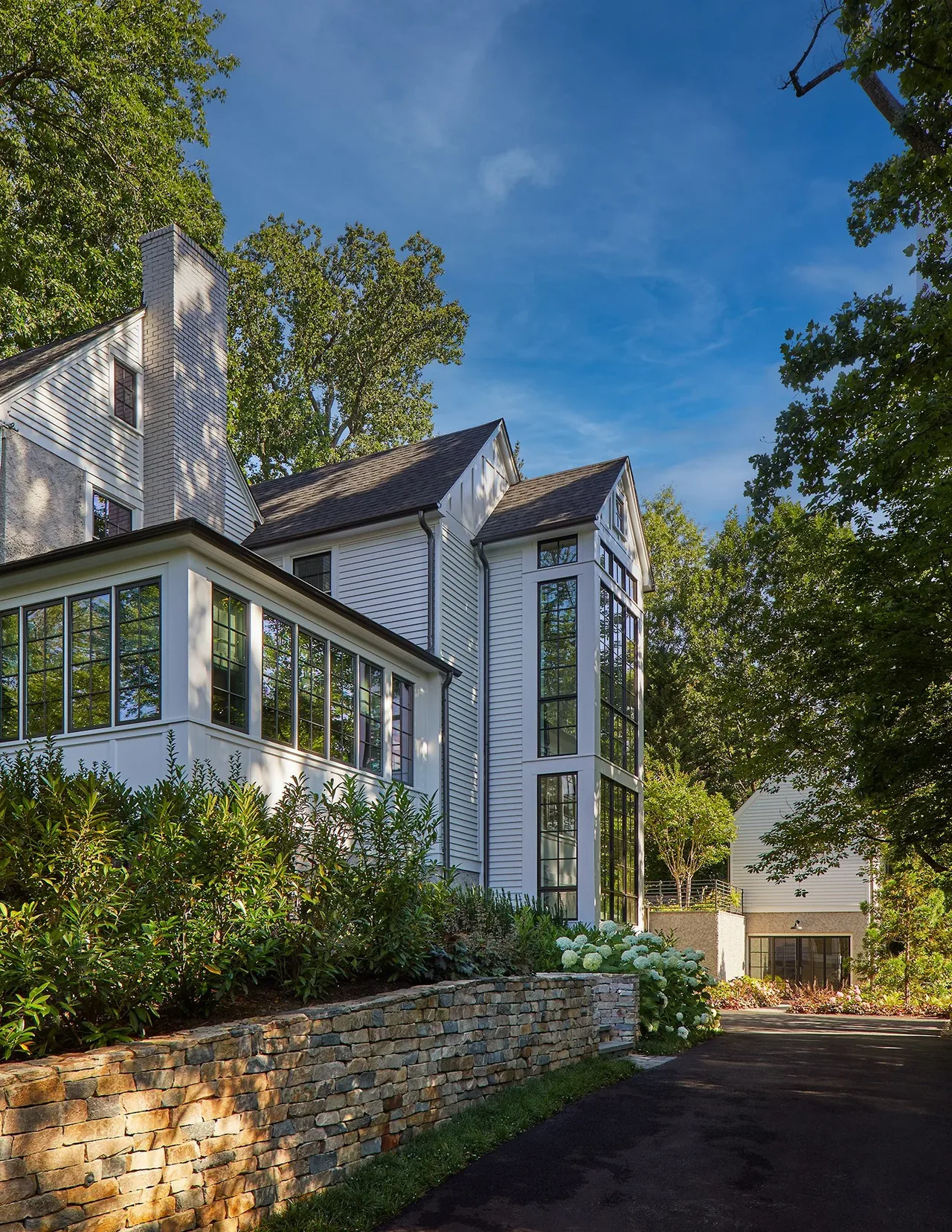 Cathedral View project features a white exterior with multi-pane leaded windows and a textured stone retaining wall by Moore Architects.