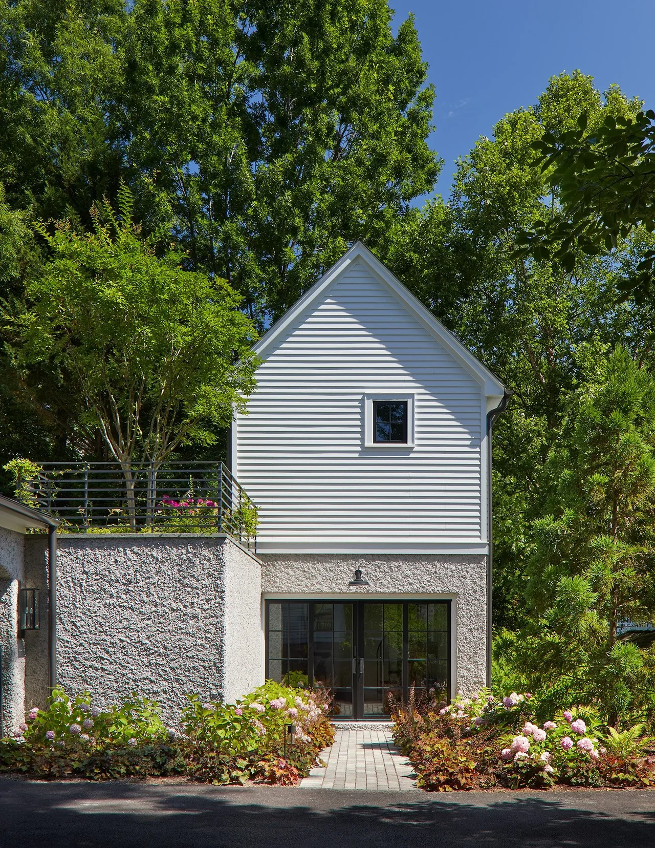 Exterior rear of the Cathedral View house showing a combination of white siding and textured concrete under blue sky.