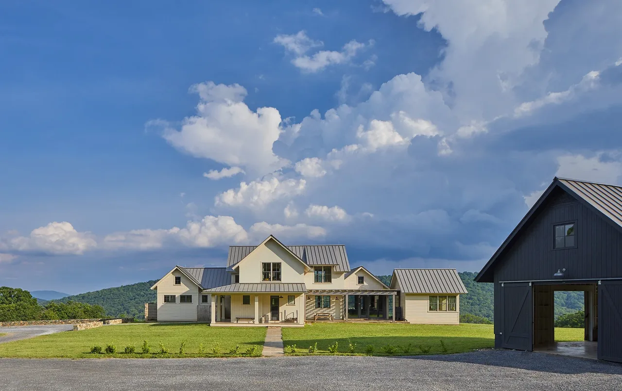 Crimson Lane Residence features metal roofs and a large lawn with stone pathway and accompanying barn building.