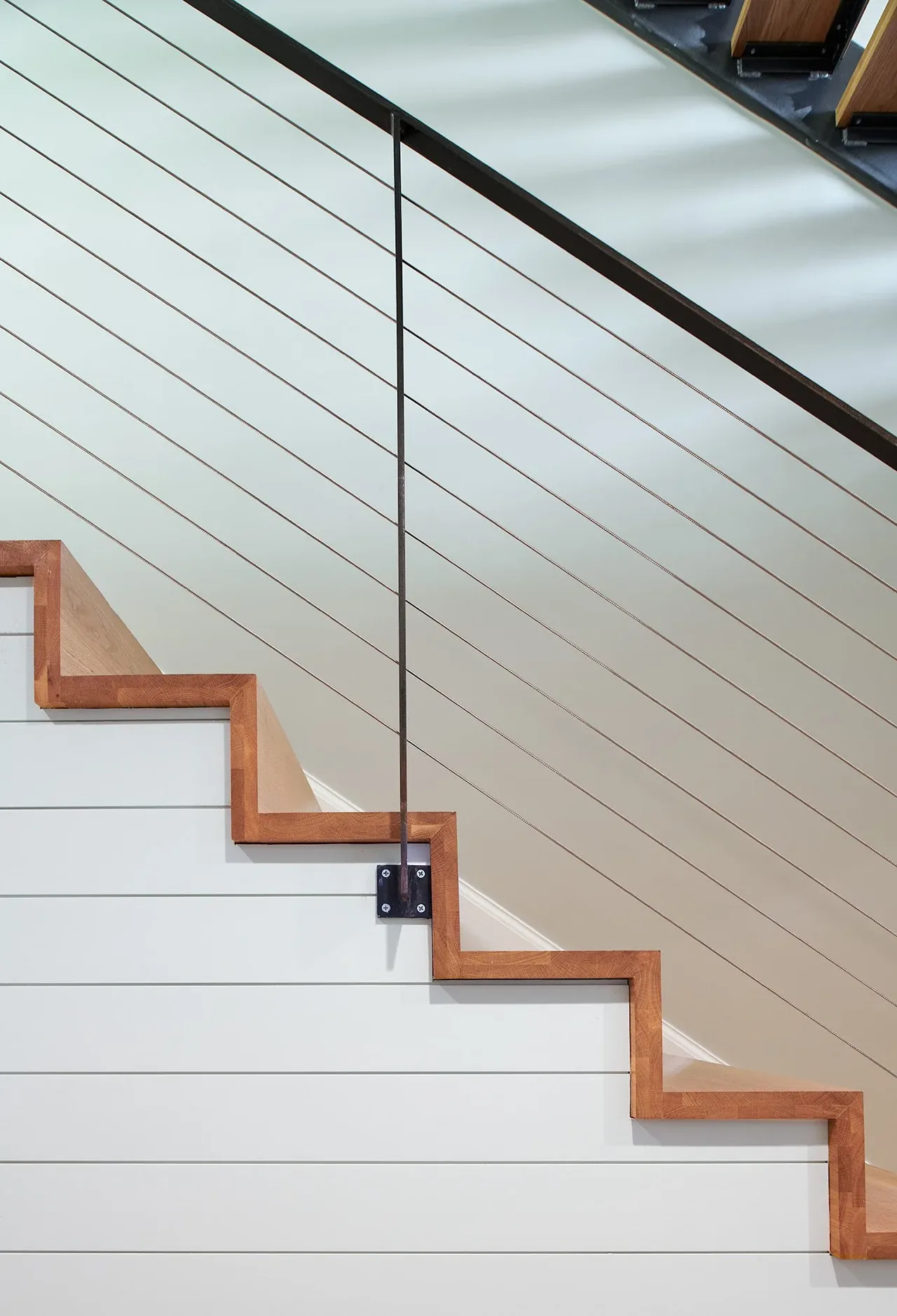 Modern staircase side view with wood trim and cable railing at the Crimson Lane Residence.