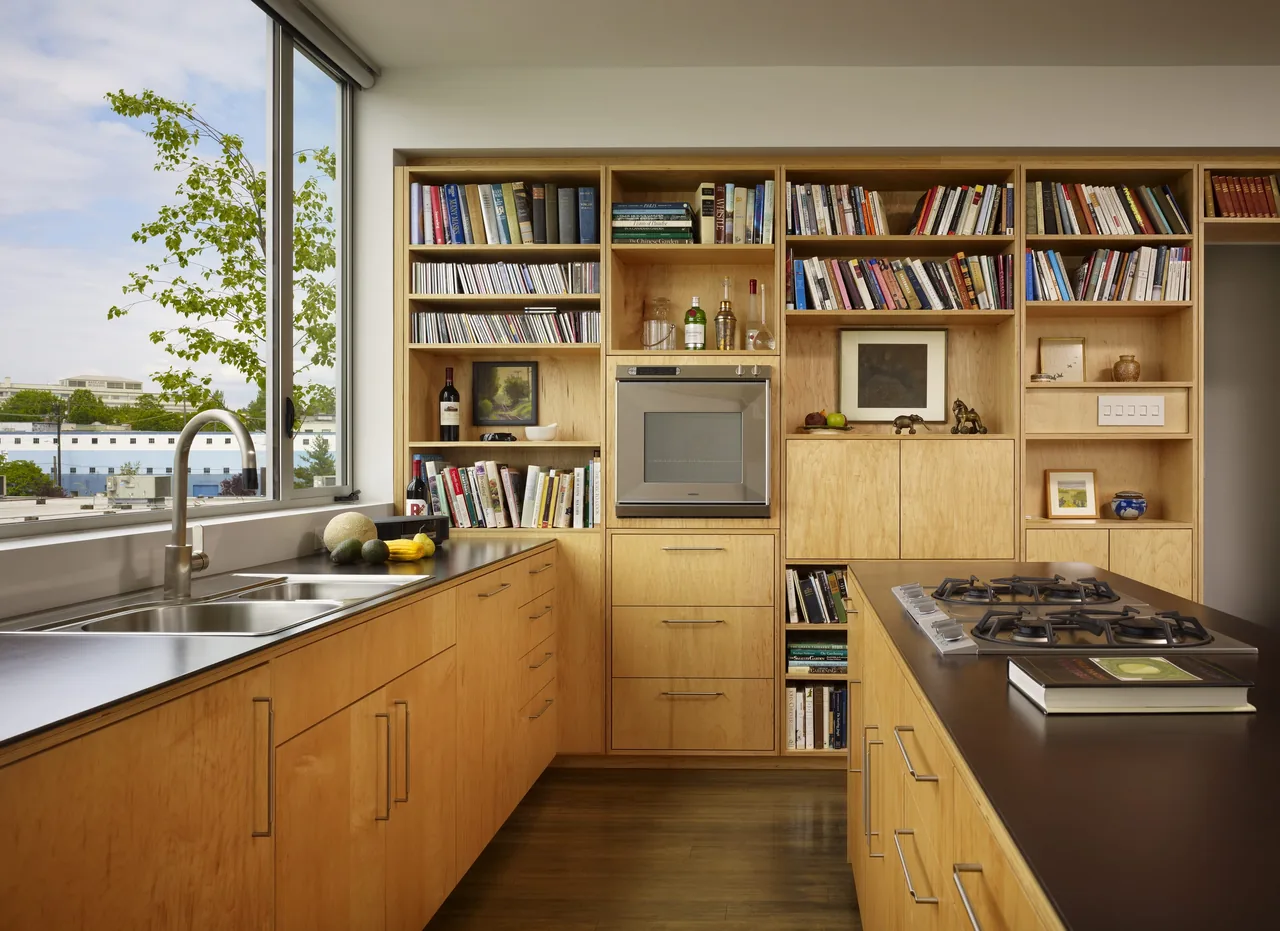 Kitchen in Sky Ranch with built-in bookshelves, double sink below large windows, and a gas cooktop on the island.