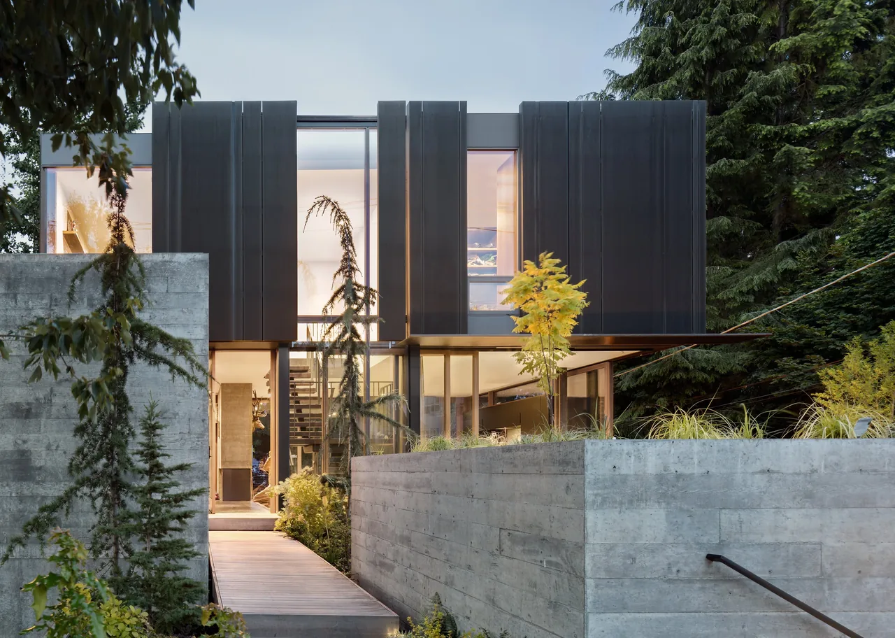 The Case Inlet Retreat features a modern design with large glazing and concrete landscaping walls.