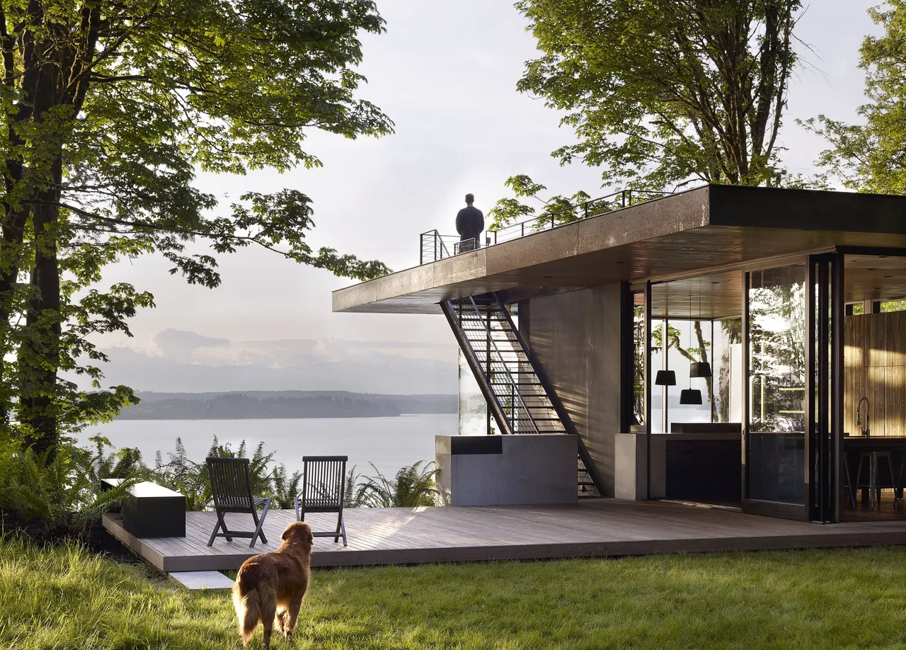 Case Inlet Retreat features a flat roof and floor-to-ceiling glazing with a lake view from the outdoor deck.