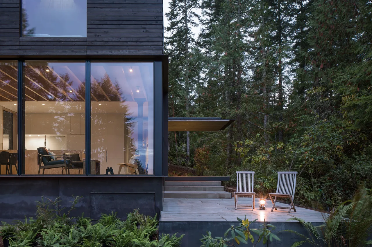 Case Inlet Retreat features floor-to-ceiling glazing and a concrete patio nestled in a forested setting near Seattle.