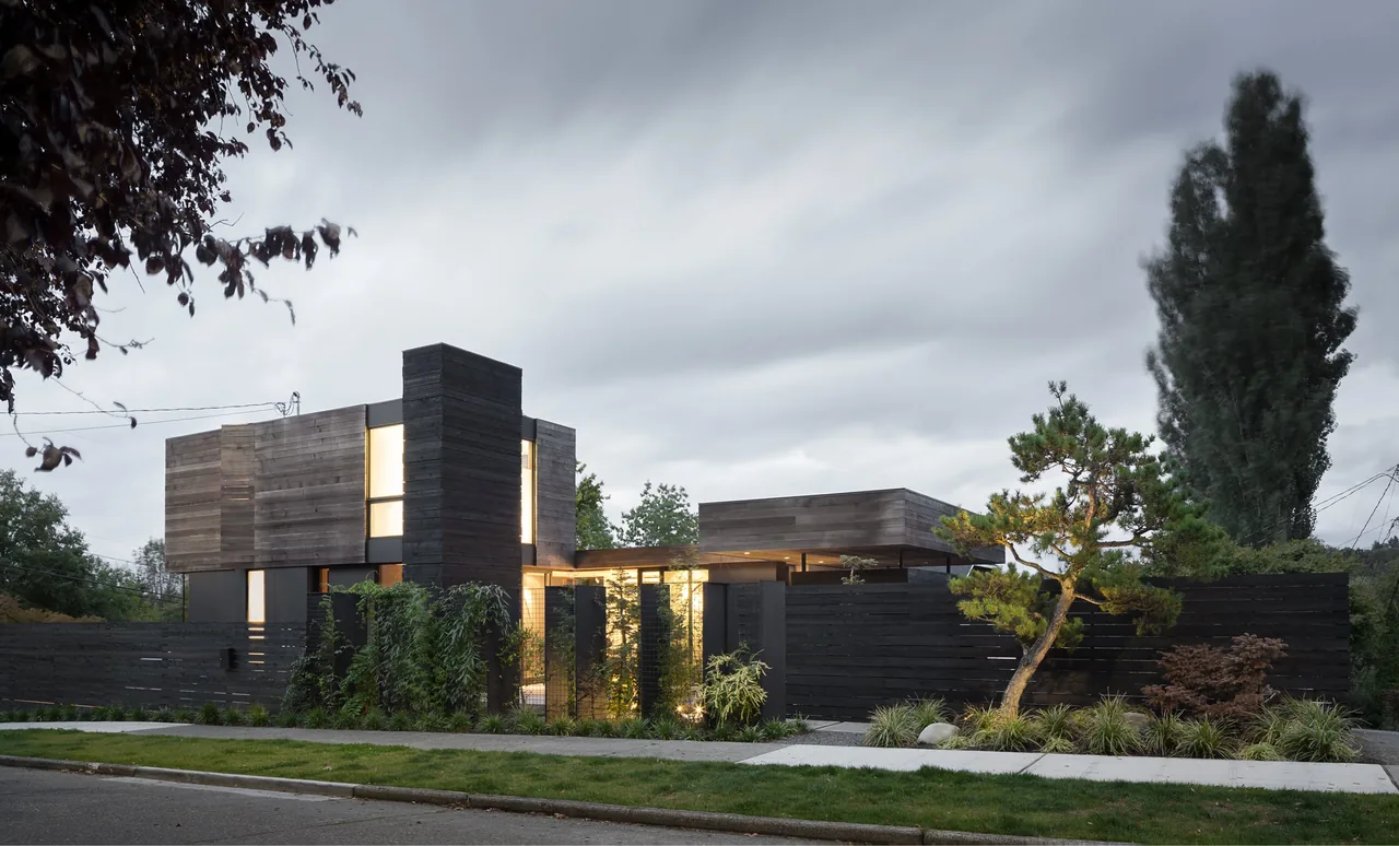 The Magnolia Residence features a modern design with dark wood siding and vertically oriented windows providing warm interior light.