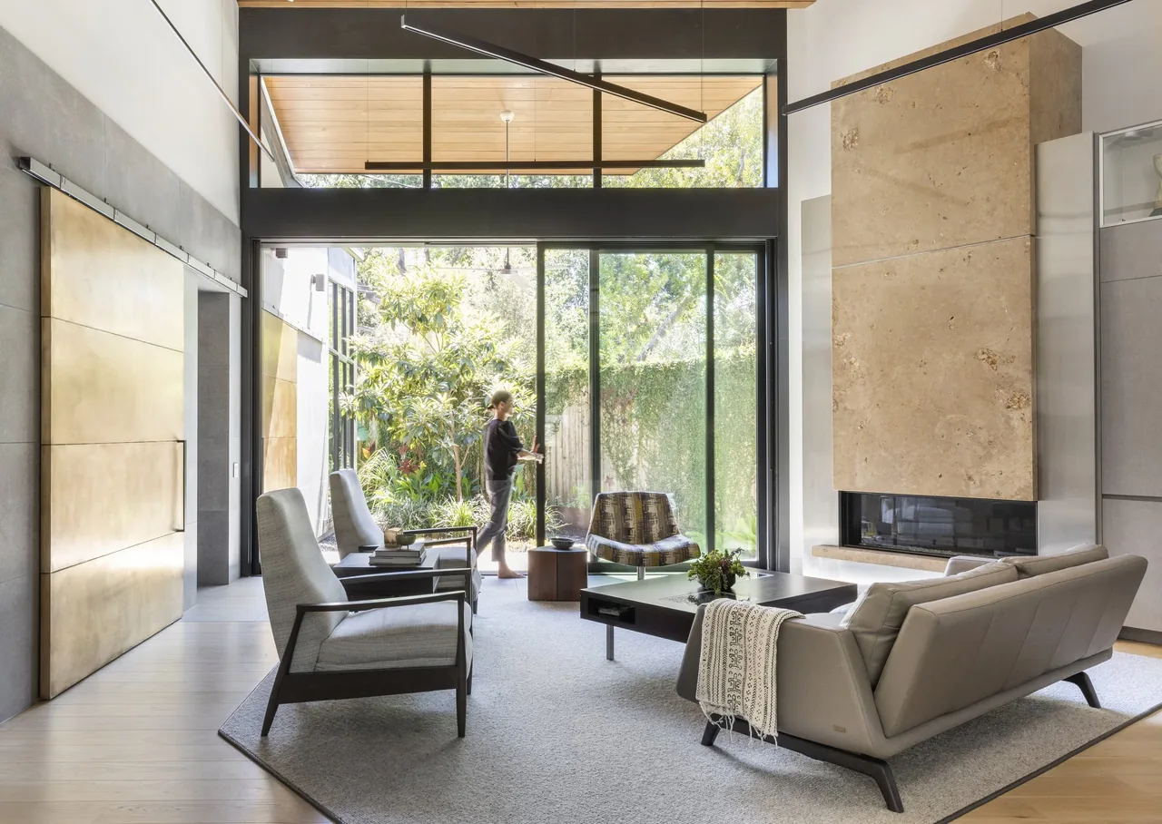 Living room at Shetland Lane House features large glazing and a stone fireplace by Natalye Appel + Associates Architects.