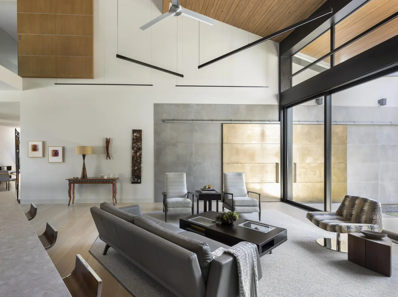 Shetland Lane House living room features floor-to-ceiling windows and a wood-paneled vaulted ceiling.