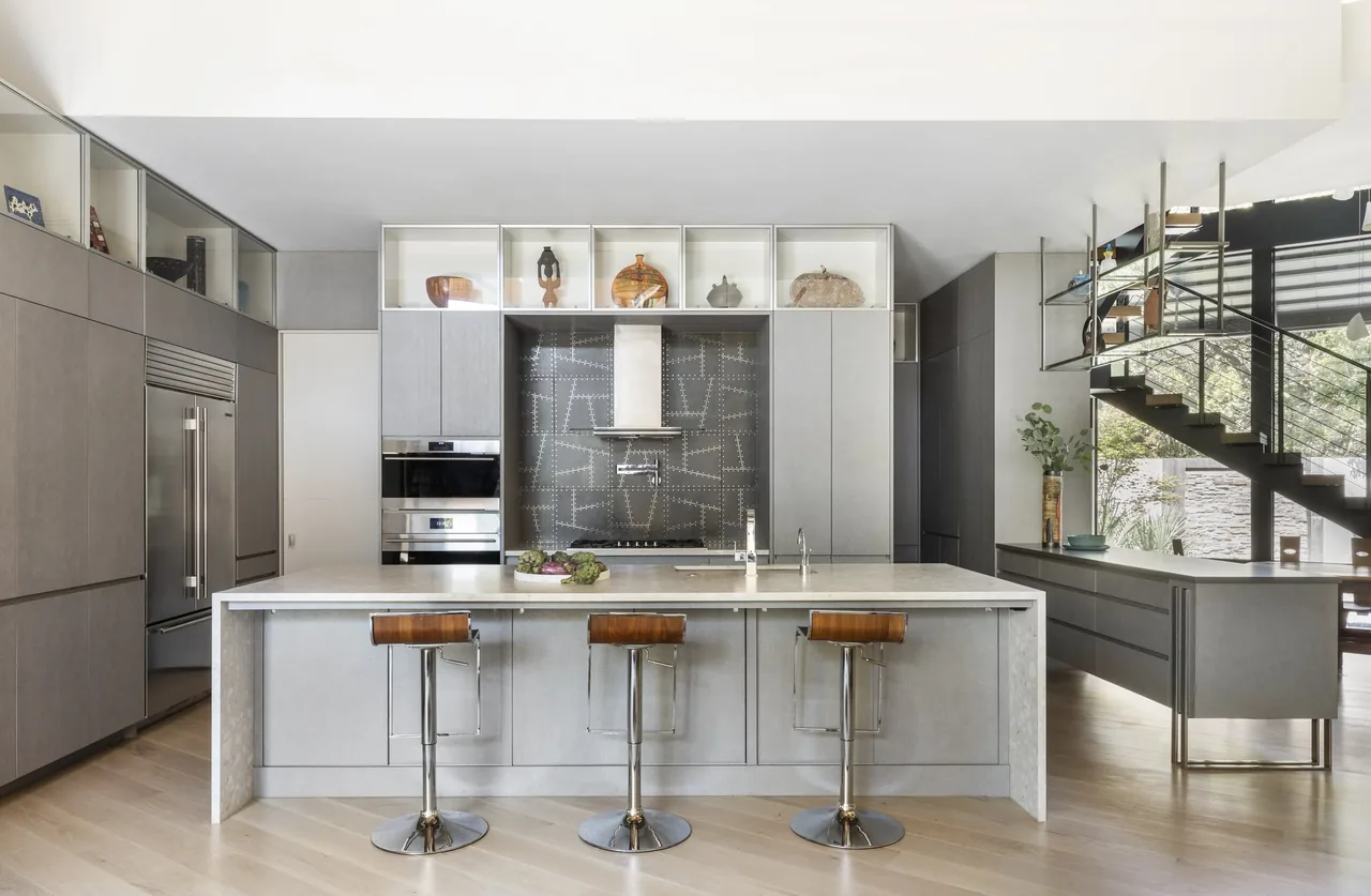 The Shetland Lane House kitchen features a large island with seating and built-in ovens, designed by Natalye Appel + Associates Architects in Houston.