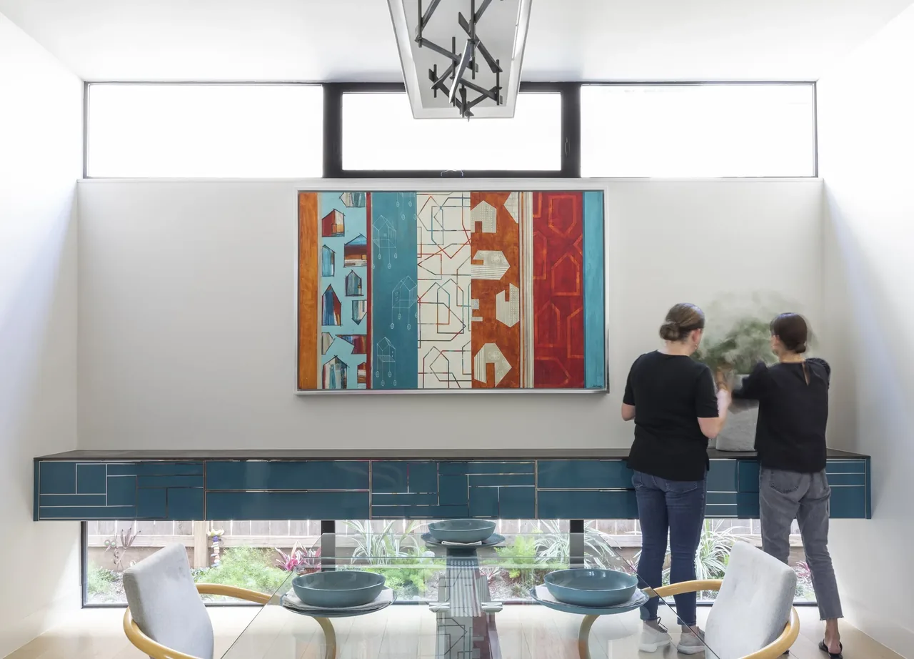 Dining area with blue floating shelf, clerestory windows above, and abstract wall art at Shetland Lane House.
