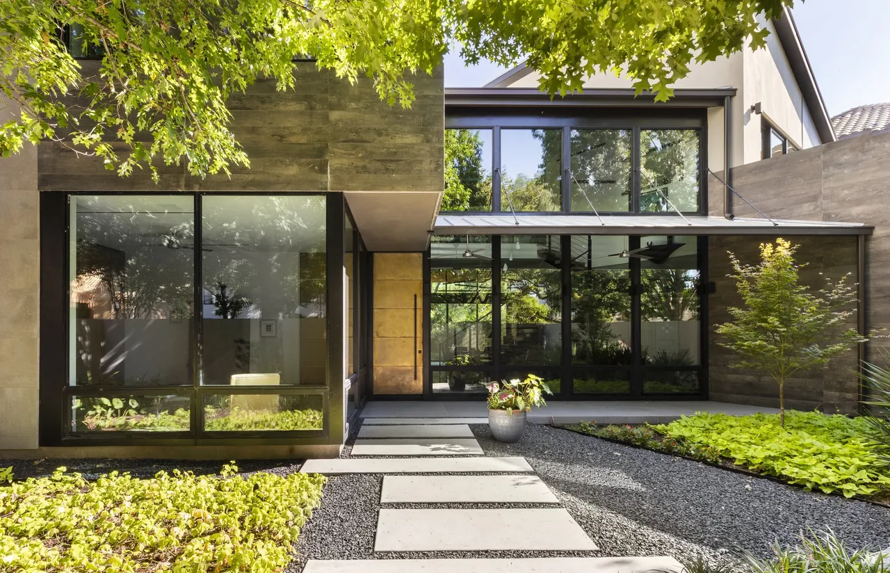 Shetland Lane House exterior features large black window frames and a landscaped pathway in front.