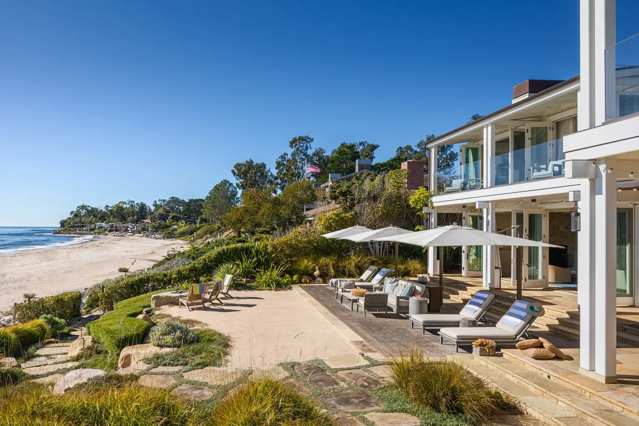 Outdoor patio with lounge chairs and umbrellas at Padaro Beach Home overlooking the beach and ocean.