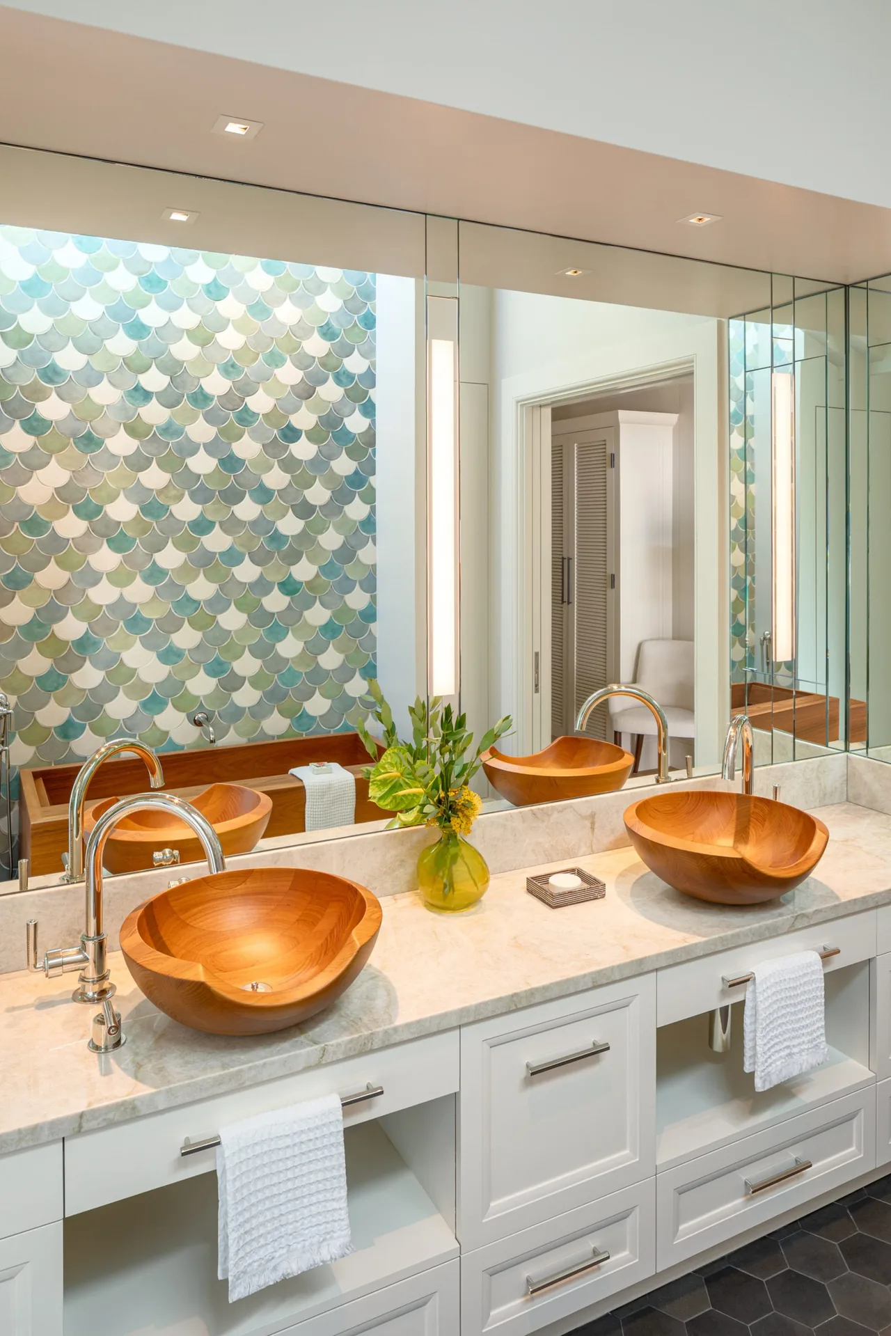 Bathroom featuring dual wooden vessel sinks on marble counter and a colorful scalloped tile accent wall.