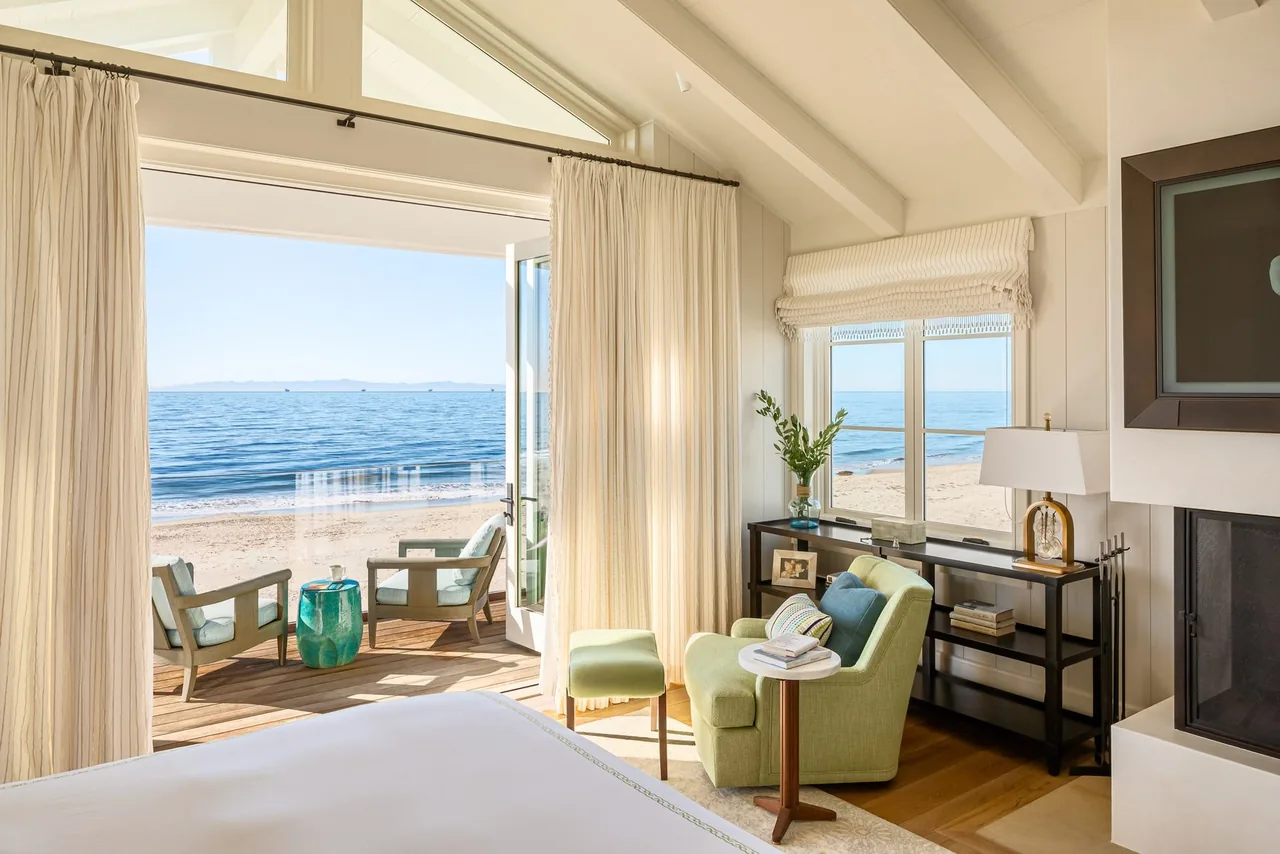 Bedroom featuring vaulted ceiling, fireplace, and direct access to a deck with ocean views.