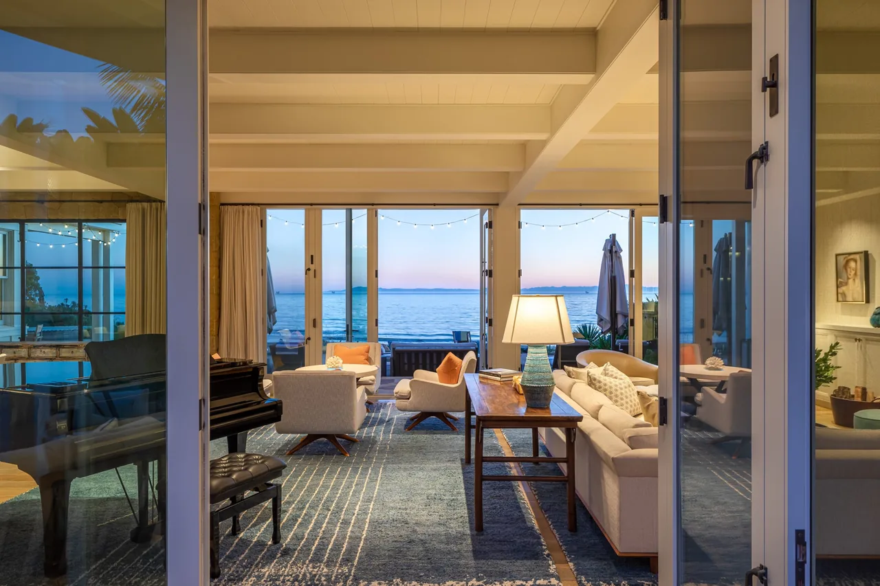 Living room with large glass doors opening to ocean views at sunset in the Padaro Beach Home.