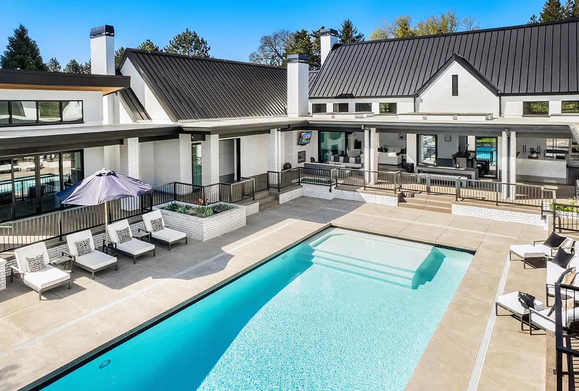 Pool area view of BURTON NEW CUSTOM BUILD featuring white brick facade and black metal roof by Nordby Design Studio Architecture & Interiors.