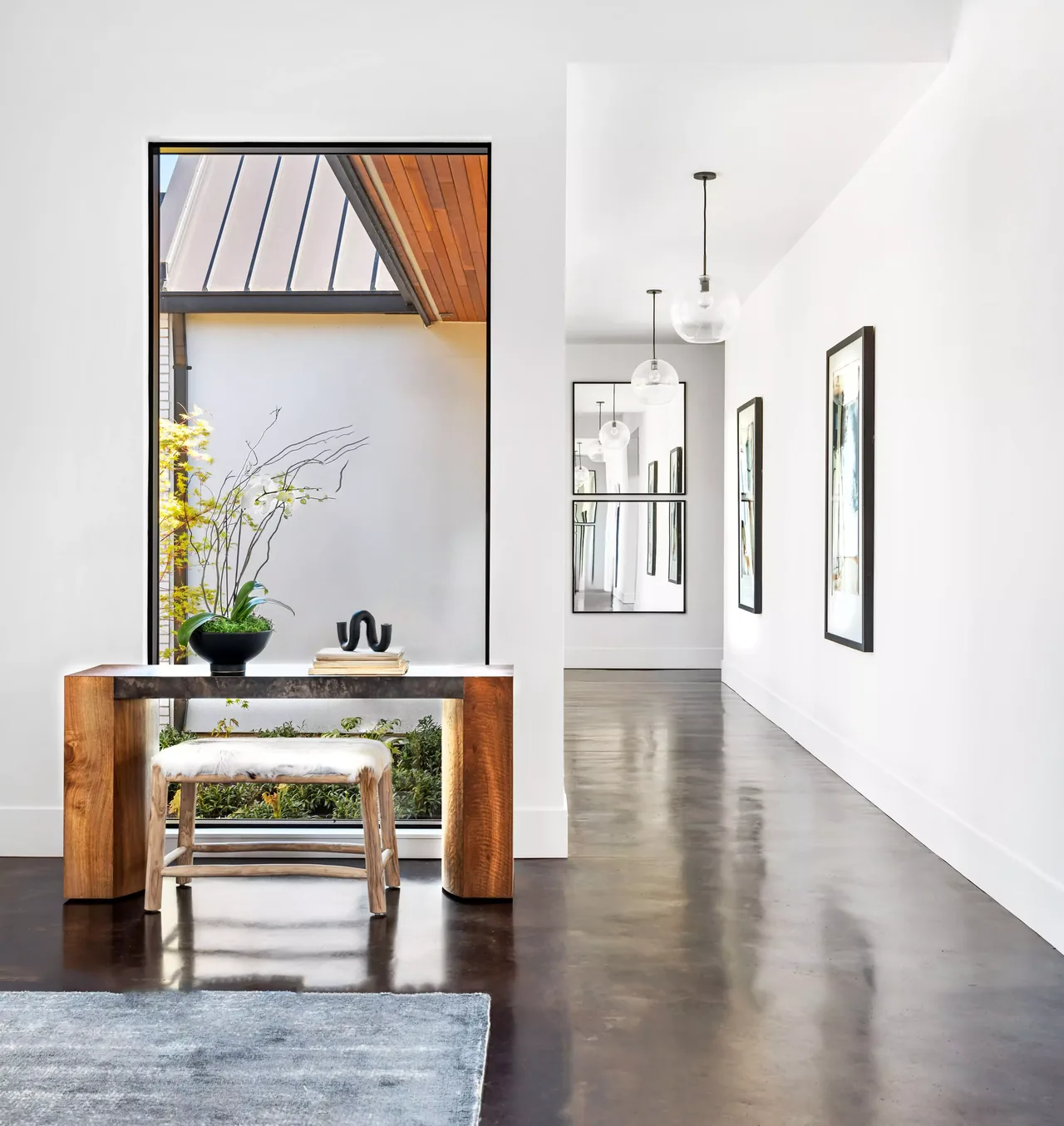 Hallway in BURTON NEW CUSTOM BUILD features polished concrete flooring and a large window showing wood ceiling detail outdoors.