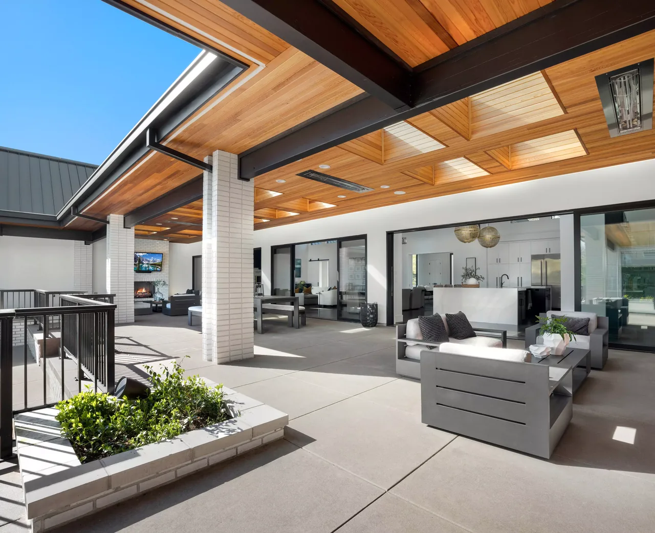 Modern covered patio featuring wood plank ceiling with skylights and direct connection to the kitchen and living rooms.