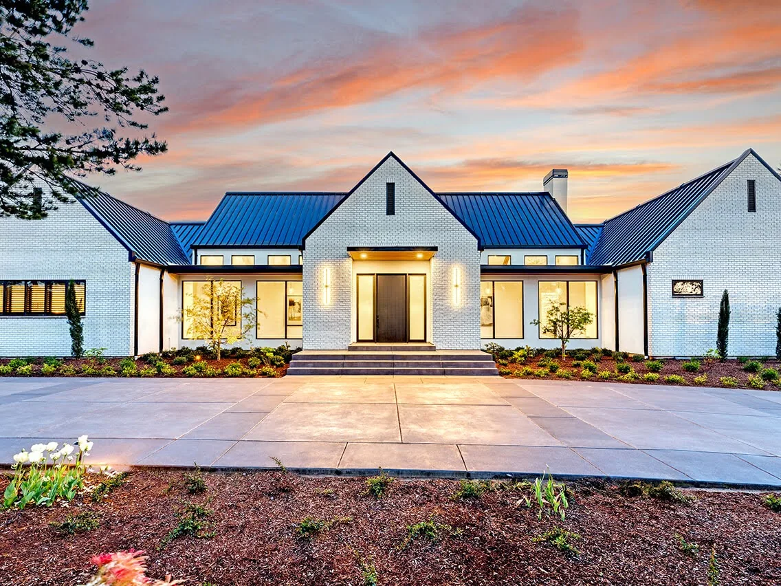 Front exterior of the BURTON NEW CUSTOM BUILD featuring white brick walls and black standing seam metal roof.