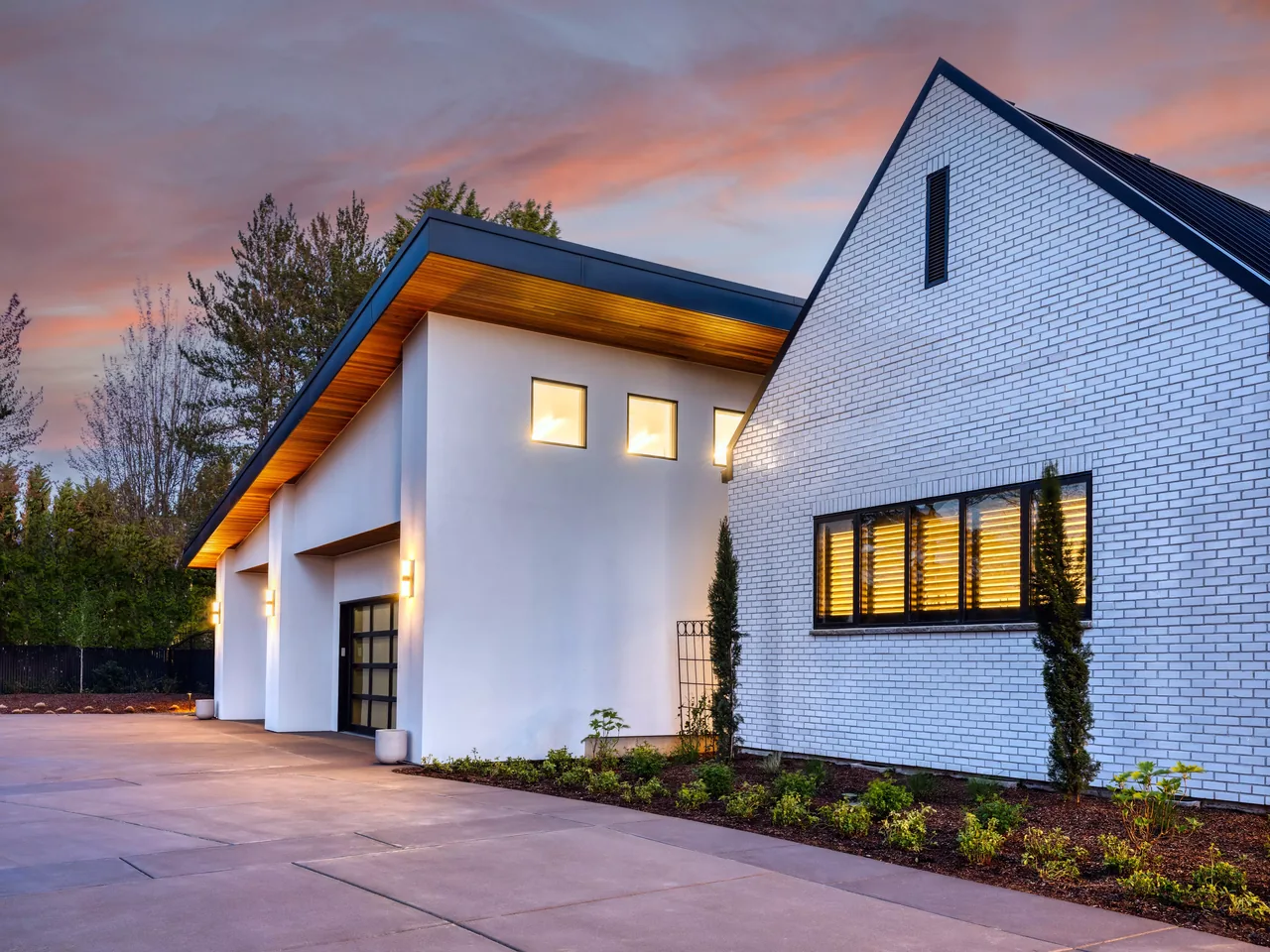 Modern residence with white brick facade and flat roof sections illuminated at dusk, designed by Nordby Design Studio Architecture & Interiors, LLC.
