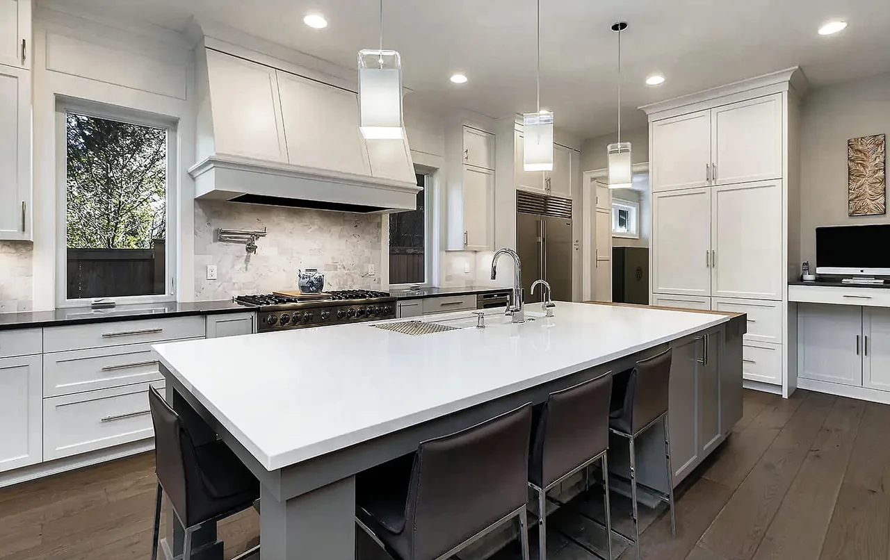 G STREET CUSTOM kitchen features a large white island with seating, pendant lights, and stainless steel appliances framed by white cabinetry.