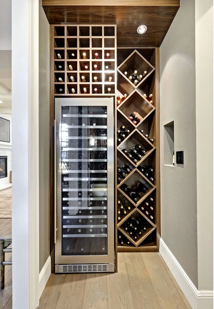This wine storage area features a stainless steel glass-front wine fridge flanked by custom wooden wine racks.