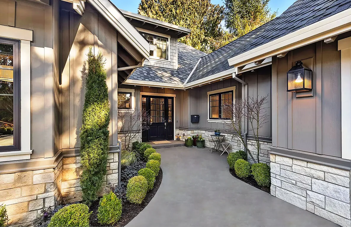 The front entry of G STREET CUSTOM features gray wood siding with stone veneer and a black-framed glass door.