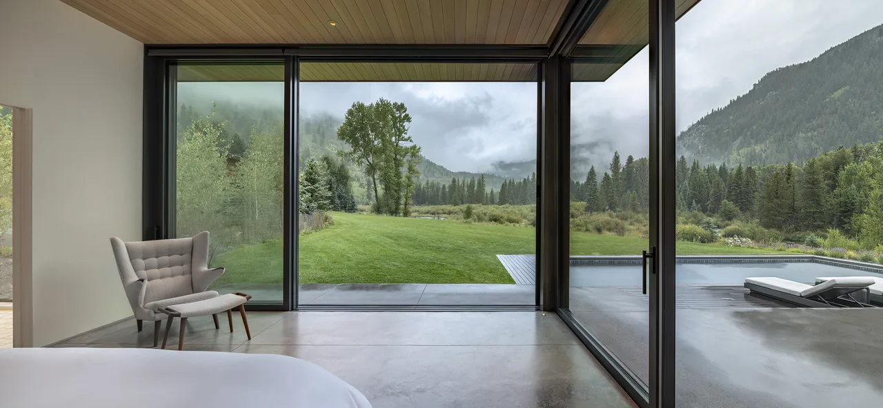 Sliding glass doors create a seamless connection from the bedroom to the outdoor pool and mountain views.