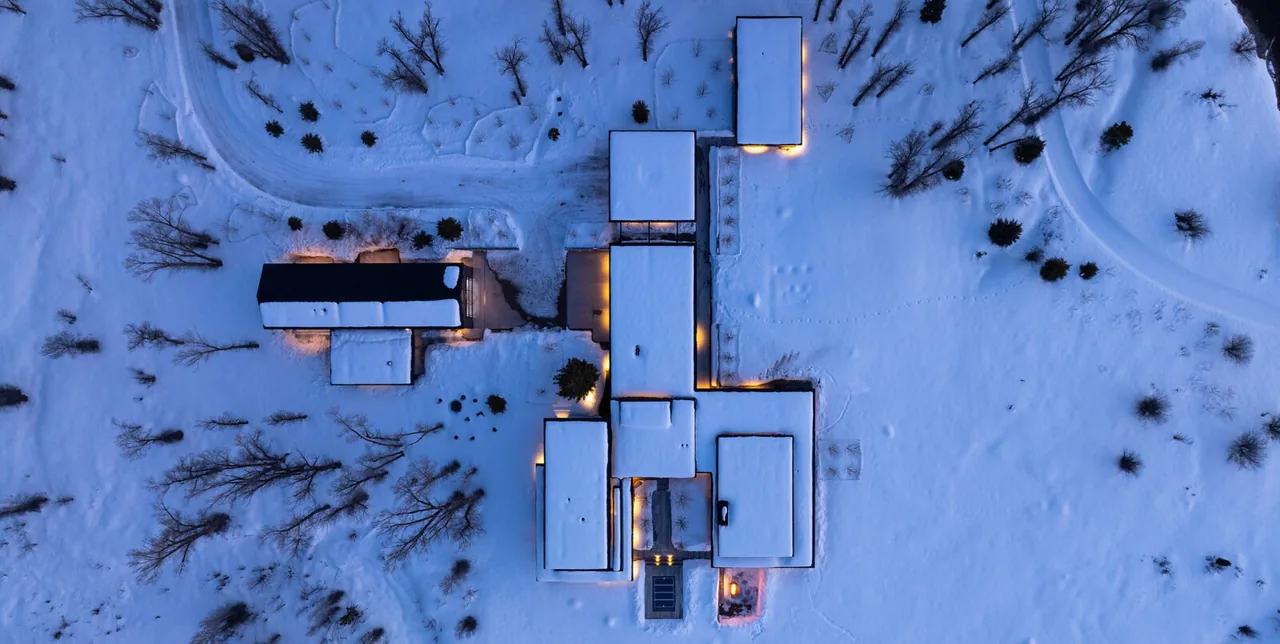 Top-down view shows the layout of a modern home with connected buildings in a snowy landscape at twilight.