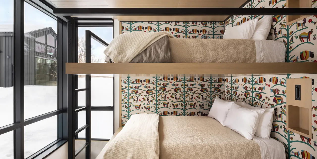 Bedroom featuring bunk beds with natural wood frames and large black-framed windows overlooking snowy exterior.