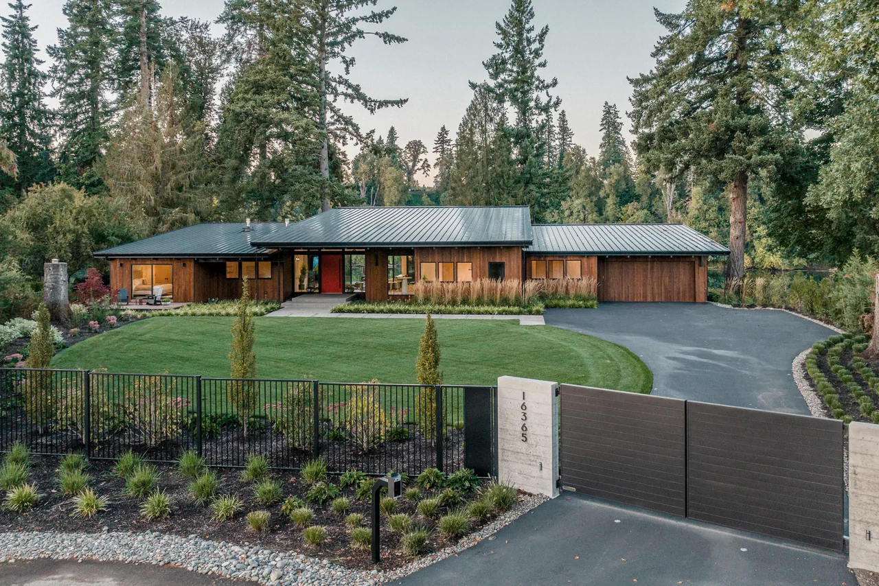 Montagne house by Paul McKean Architecture features wood siding and a standing seam metal roof in a forested setting.