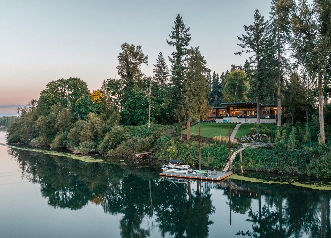 The Montagne project features a contemporary home set on a wooded riverbank with a private dock.