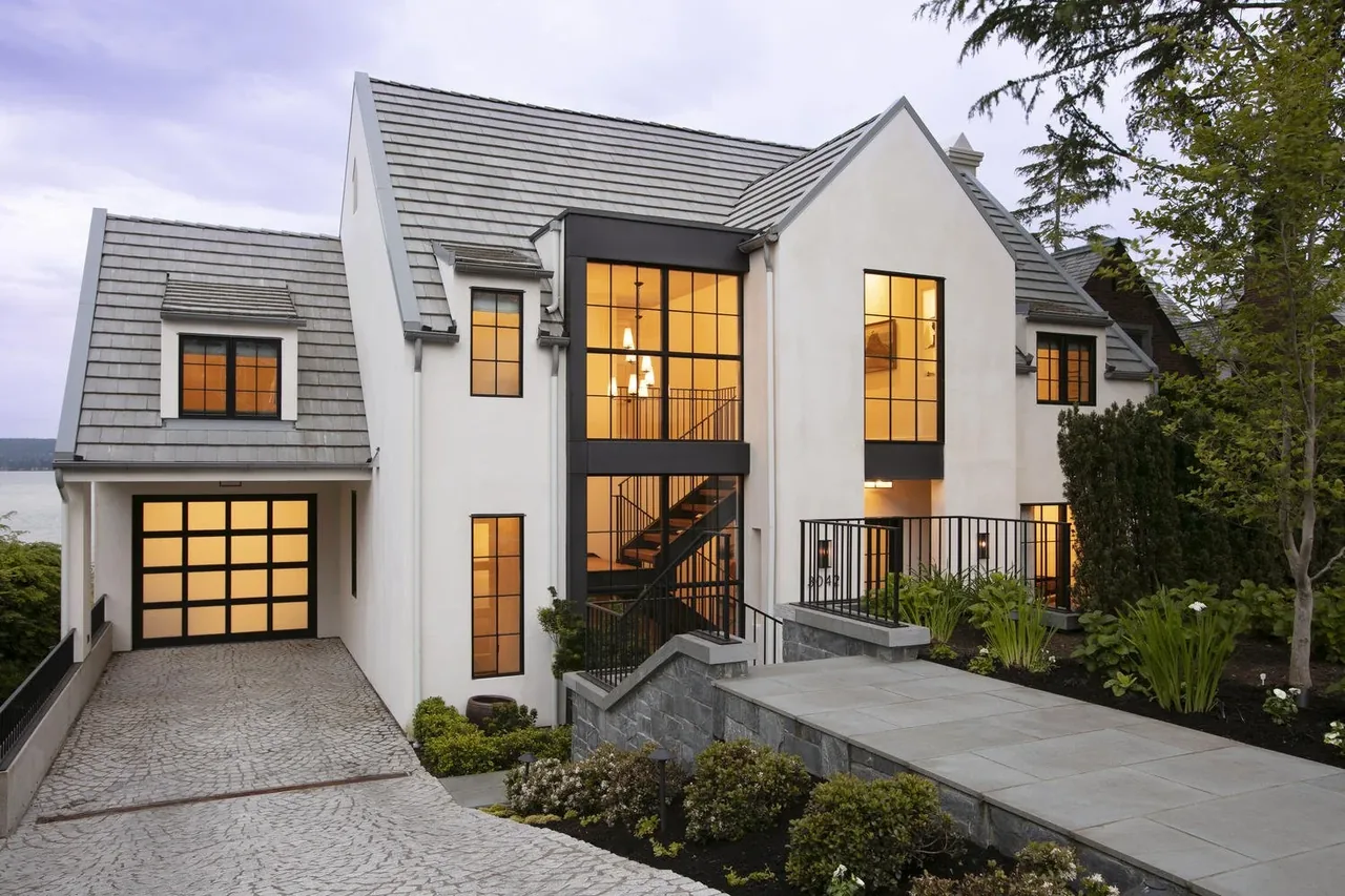 Laurelhurst Contemporary features black-framed windows and a gable roof with a white stucco exterior and stone entryway.