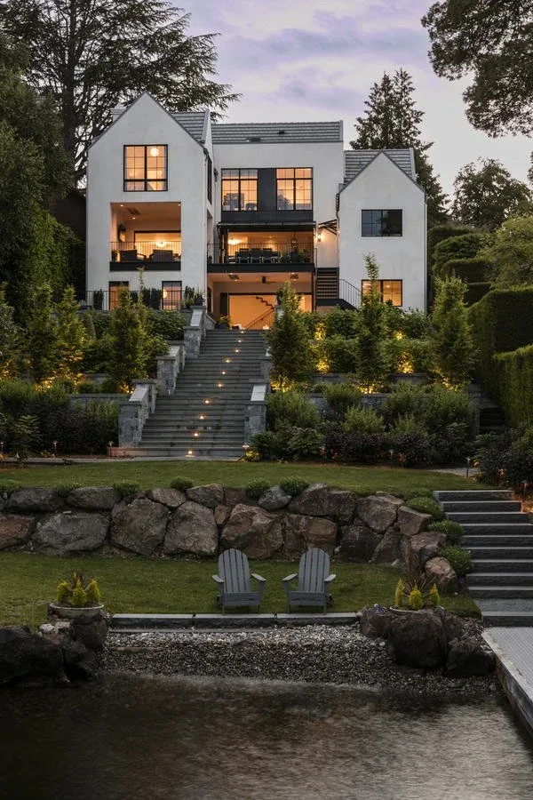 Laurelhurst Contemporary house by Paul Moon Design shows a modern exterior with stucco walls, black-framed windows, and tiered landscaping with stair lighting.