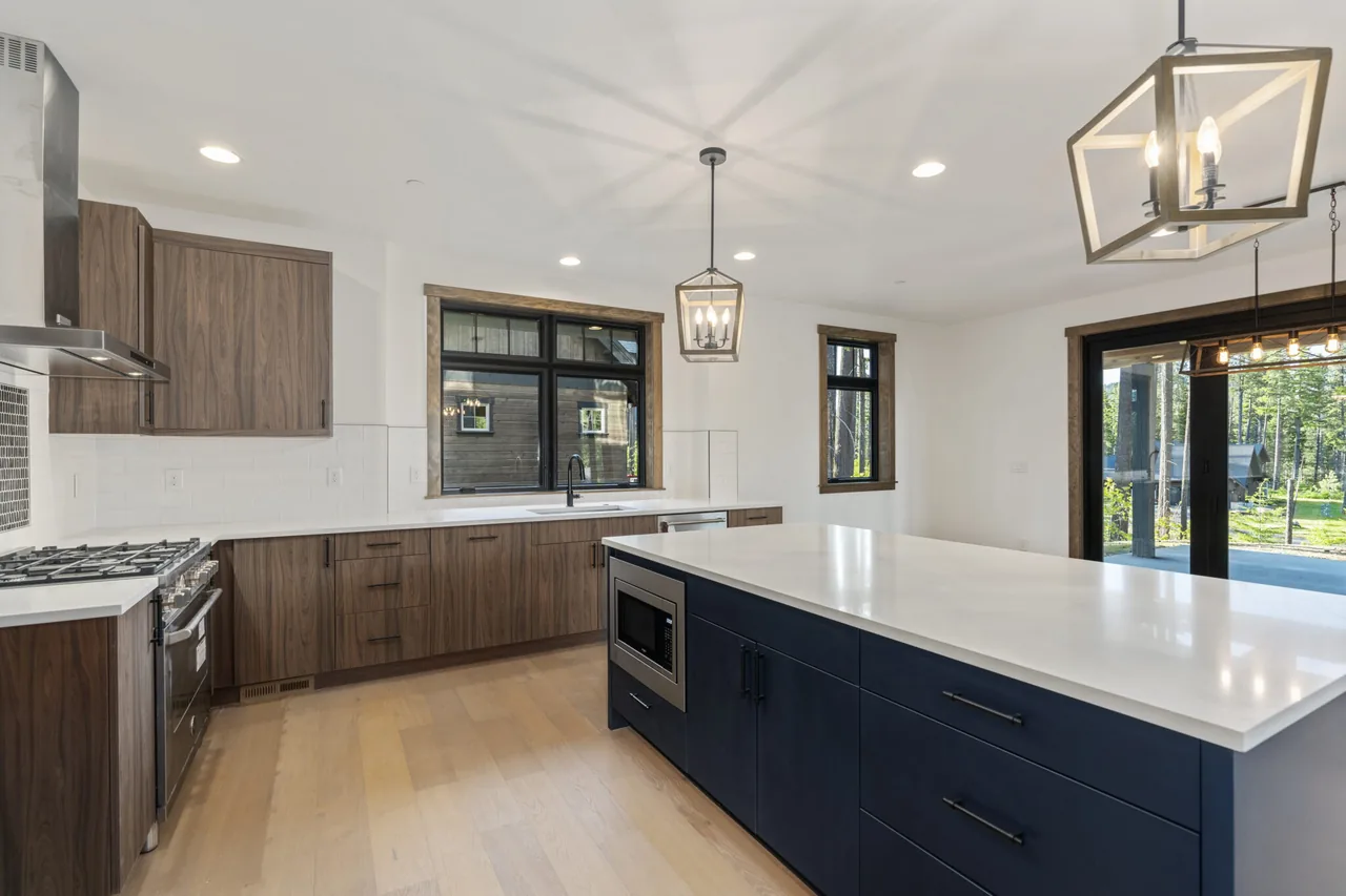 This kitchen features dark wood cabinetry, a navy kitchen island with a white countertop, and stainless steel appliances.