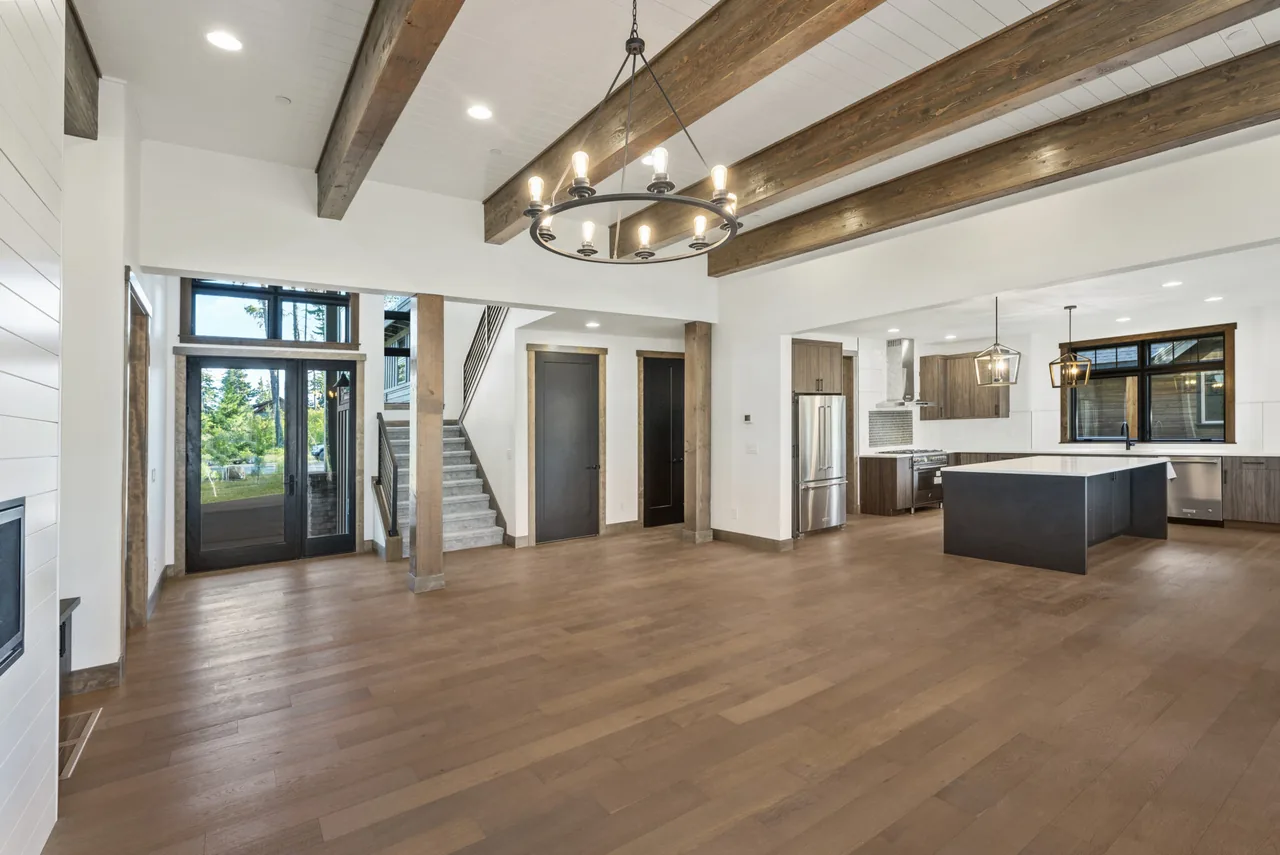 Open living and kitchen area with vaulted ceiling, wood beams, and large windows at 360 King's Court by Page & Beard Architects.